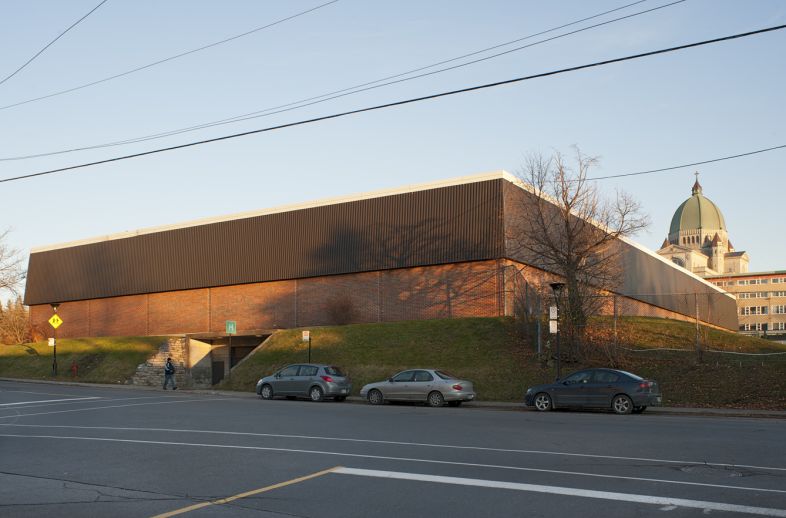 La façade nord de l’aréna donne sur la rue Jean-Brillant. Implanté sur un talus, le bâtiment comporte des accès au niveau du sous-sol. Photographie.