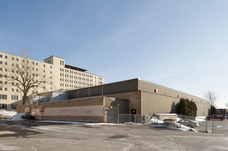 Élévation est de l'aréna Lassonde-Oasis. Toutes les façades du bâtiment sont aveugles et composées de matériaux sobres, soit la brique et la tôle. Photographie.