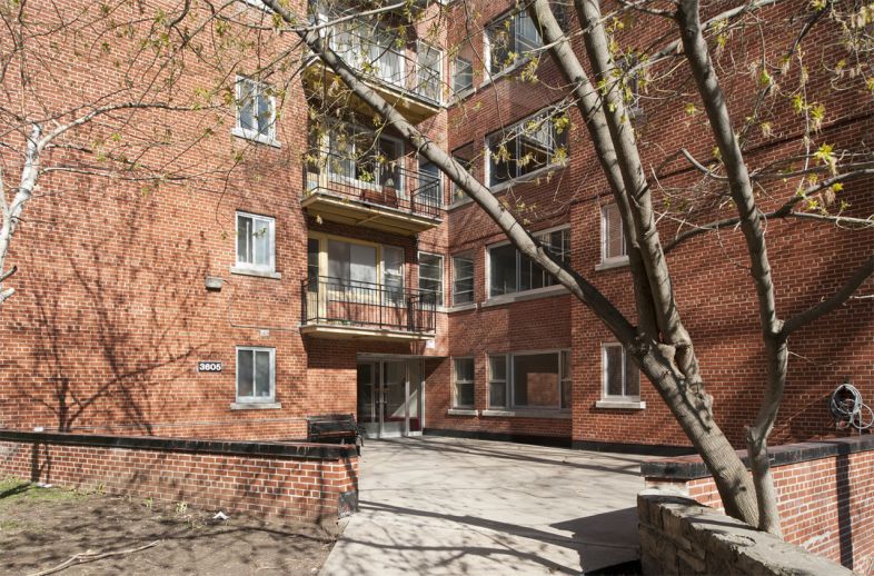 La terrasse surélevée de l’entrée des appartements Summit profite du plan cruciforme de l’immeuble pour s’implanter dans une de ses articulations. Le portail d’entrée très discret s’efface à travers les autres ouvertures.