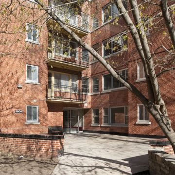 La terrasse surélevée de l’entrée des appartements Summit profite du plan cruciforme de l’immeuble pour s’implanter dans une de ses articulations. Le portail d’entrée très discret s’efface à travers les autres ouvertures.